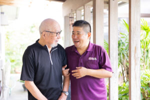 スタッフが入居者と談笑する日常風景。施設内の廊下で交流する様子。
